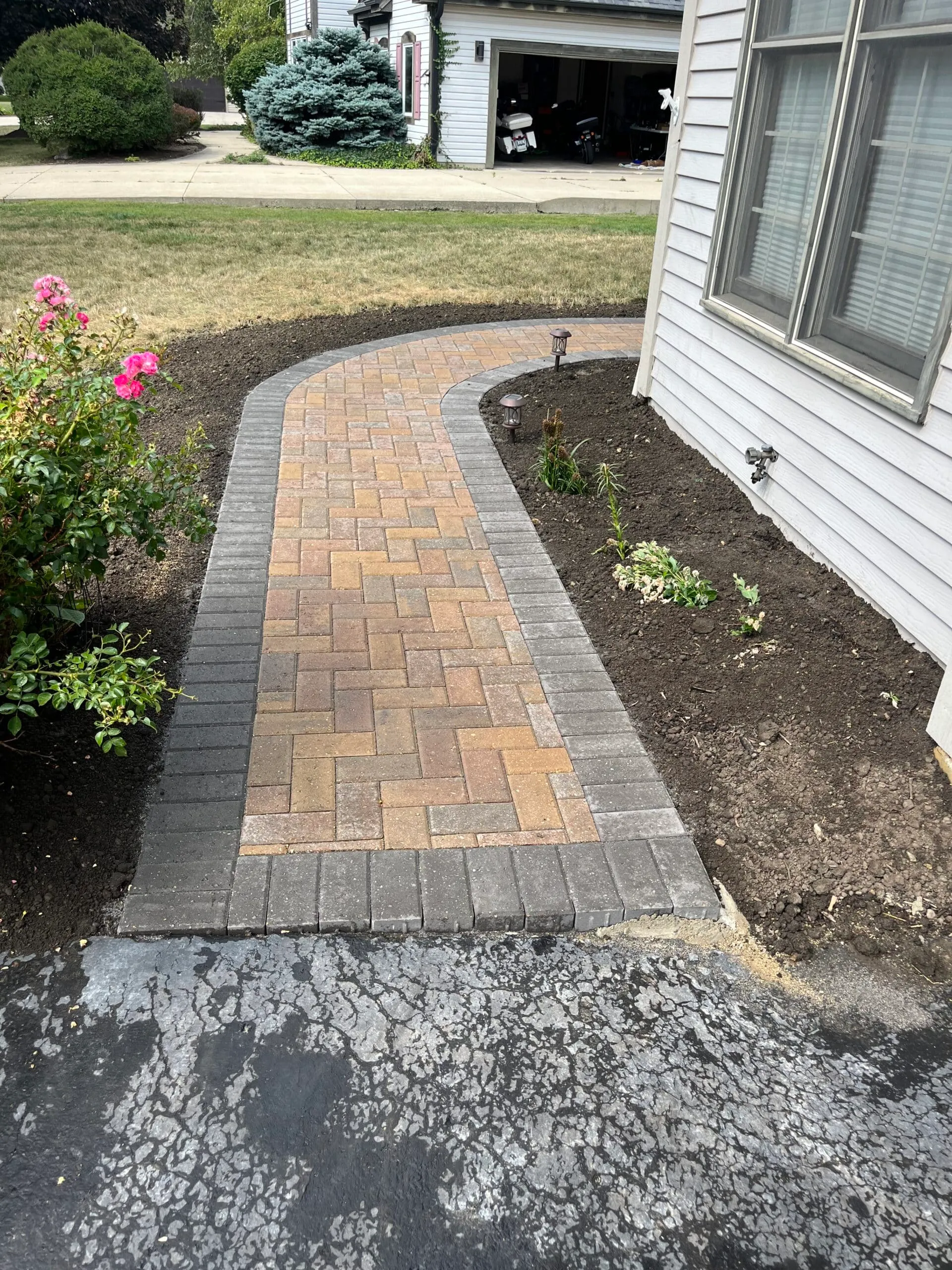 Tan paver walkway beside driveway